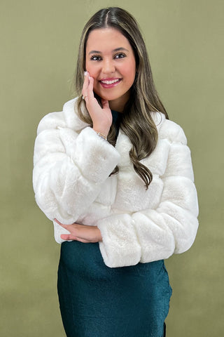 Woman wearing a white fur coat against a green background