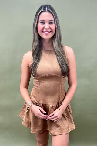 Woman wearing a brown romper against a green background