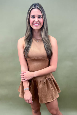 Woman wearing a brown sleeveless top and shorts set against a green background