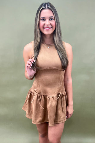 Woman wearing a brown dress against a green background