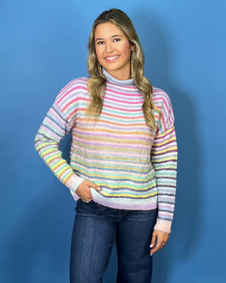 Pastel multicolor striped knit sweater with a cozy mock neckline, long sleeves and relaxed fit.