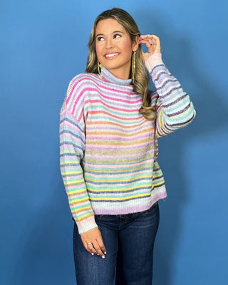 Pastel multicolor striped knit sweater with a cozy mock neckline, long sleeves and relaxed fit.