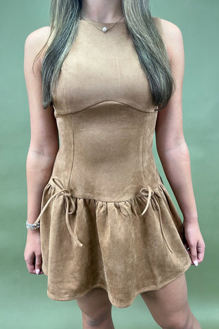 Woman wearing a brown suede dress against a green background
