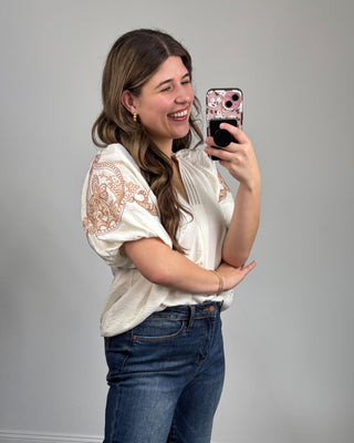 Woman taking a selfie with a floral phone case against a plain background