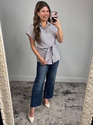 Woman taking a mirror selfie wearing a striped shirt and jeans.