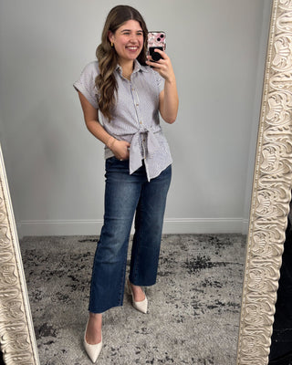 Woman taking a mirror selfie wearing a striped shirt and jeans in a room with decorative mirrors.