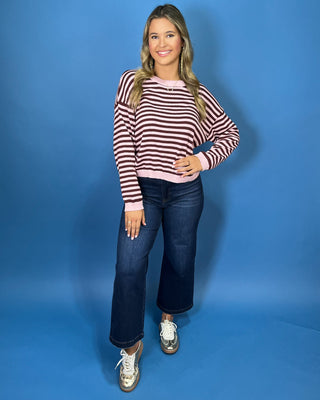 Pink and chocolate brown striped knit sweater with long sleeves, crew neckline and relaxed fit.