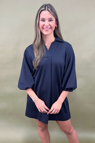 Woman wearing a navy blue dress against a beige background