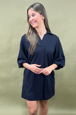 Woman wearing a navy blue dress against a beige background