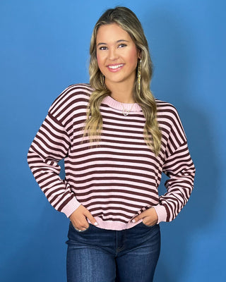 Pink and chocolate brown striped knit sweater with long sleeves, crew neckline and relaxed fit.