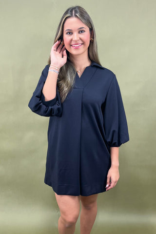 Woman wearing a navy blue dress against a green background