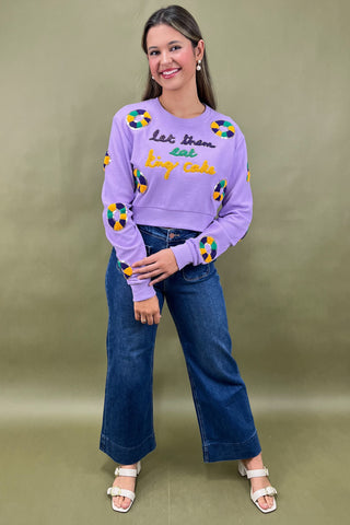 Woman wearing a purple sweater with colorful text and designs on a green background