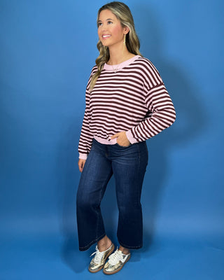Pink and chocolate brown striped knit sweater with long sleeves, crew neckline and relaxed fit.