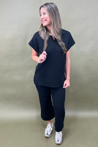 Woman wearing a black outfit with white sneakers on a plain background