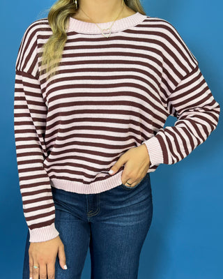 Pink and chocolate brown striped knit sweater with long sleeves, crew neckline and relaxed fit.