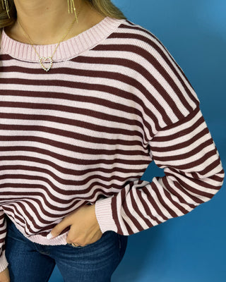 Pink and chocolate brown striped knit sweater with long sleeves, crew neckline and relaxed fit.