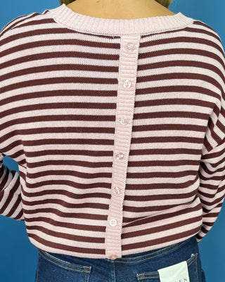 Pink and chocolate brown striped knit sweater with long sleeves, crew neckline and relaxed fit.