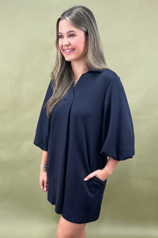 Woman wearing a navy blue dress against a green background