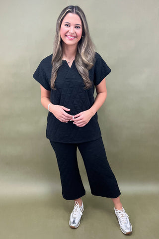Woman wearing a black outfit with white sneakers on a green background