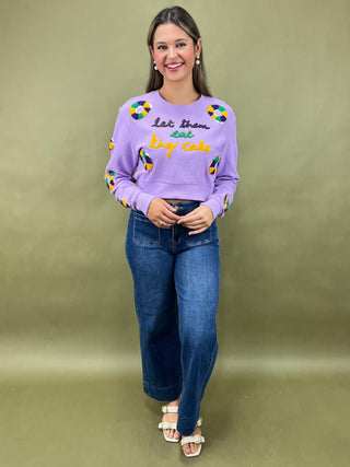 Woman wearing a purple sweater with colorful text and designs on a green background