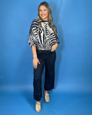 Navy and ivory zebra print top with a high neckline, button-front detail, puff sleeves, and a relaxed fit.