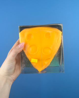 The Big Cheese Triangle Squishy held up against a solid blue background.  