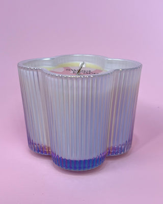 Iridescent glass candle holder with a pink candle on a pink background