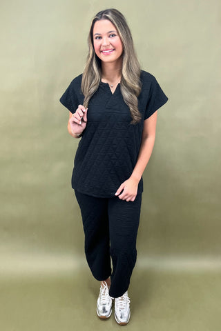 Woman wearing a black outfit with white sneakers on a green background