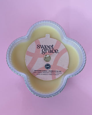 Sweet Grace candle in a clear container on a pink background