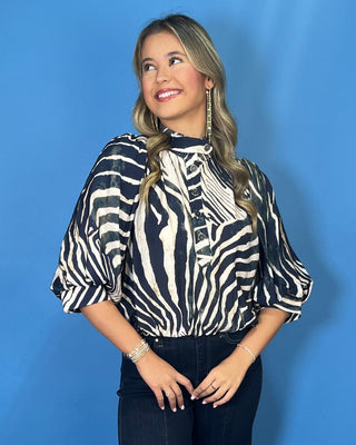 Navy and ivory zebra print top with a high neckline, button-front detail, puff sleeves, and a relaxed fit.