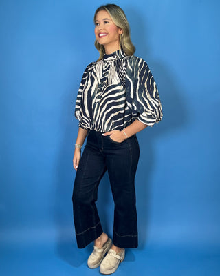 Navy and ivory zebra print top with a high neckline, button-front detail, puff sleeves, and a relaxed fit.