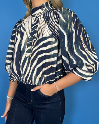Navy and ivory zebra print top with a high neckline, button-front detail, puff sleeves, and a relaxed fit.