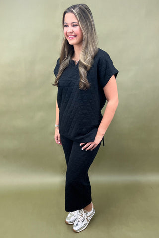 Woman wearing a black outfit with white sneakers on a beige background