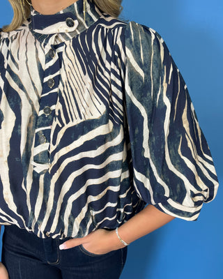 Navy and ivory zebra print top with a high neckline, button-front detail, puff sleeves, and a relaxed fit.