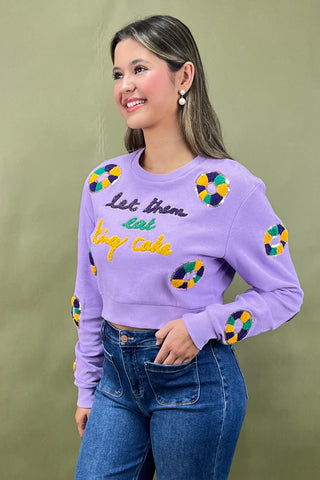 Woman wearing a purple sweater with colorful designs and text on a green background