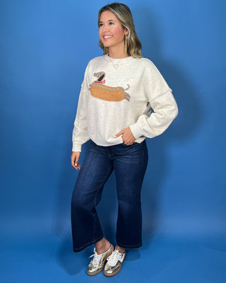 Ivory knit sweater with long sleeves, relaxed fit and a playful dachshund hot dog graphic.