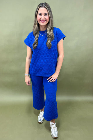 Woman wearing a blue outfit with white sneakers on a green background