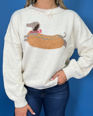 Ivory knit sweater with long sleeves, relaxed fit and a playful dachshund hot dog graphic.