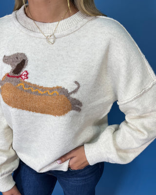 Ivory knit sweater with long sleeves, relaxed fit and a playful dachshund hot dog graphic.