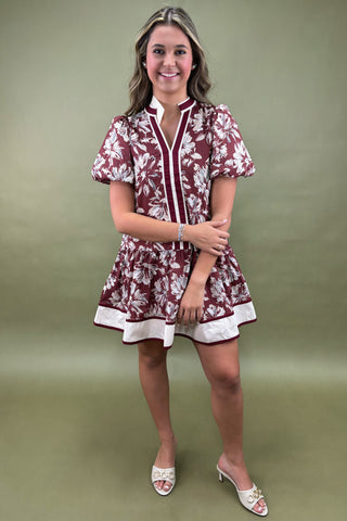 Woman wearing a maroon and white floral dress against a green background