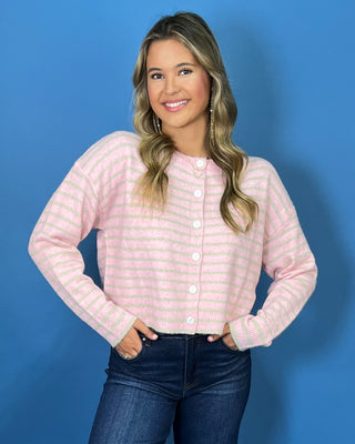 Pink and ivory striped knit cardigan with a round neckline, long sleeves, relaxed fit, and white button-front closure.