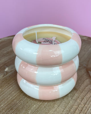 Pink and white striped candle with 'sweet magic' text on a wooden surface and pink background