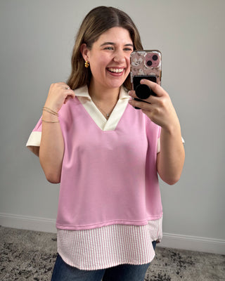 Woman taking a mirror selfie wearing a pink sleeveless top with a white collar.