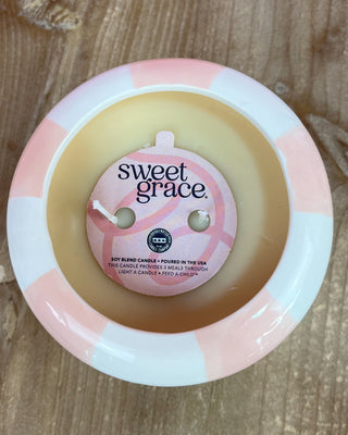 Sweet Grace candle with a pink and white label on a wooden surface