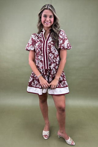 Woman wearing a maroon floral dress against a green background