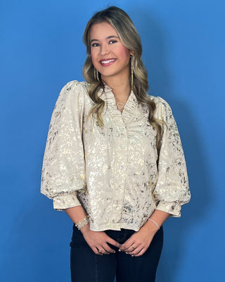 Ivory metallic blouse with abstract shimmer, ruffled V-neckline, button front, and puff sleeves.