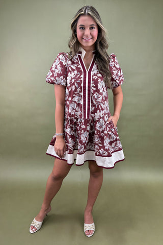 Woman wearing a maroon floral dress against a green background