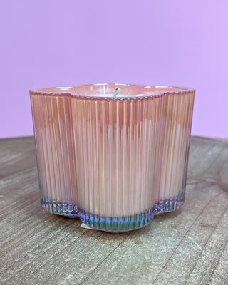 Cylindrical candle with ribbed design on a wooden surface and purple background