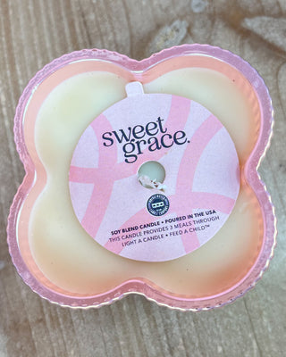 Heart-shaped candle with 'sweet grace' branding on a wooden surface
