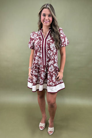 Woman wearing a maroon floral dress against a green background